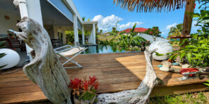 Deck en bois au bord de la piscine de la Villa Corail entouré du jardin tropical