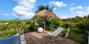 Espace détente au bord de la piscine de la Villa Corail avec transat et jardin tropical