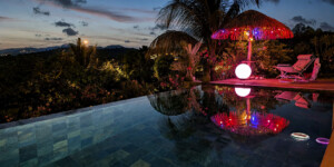 Piscine à débordement de la Villa Corail au crépuscule avec espace détente éclairé